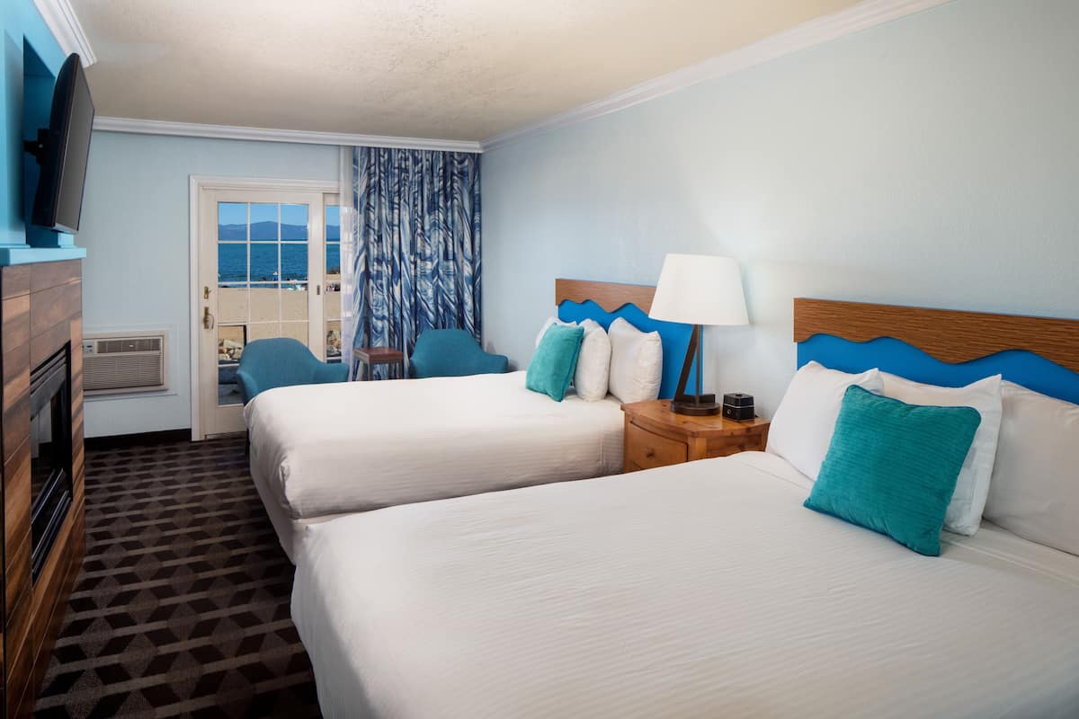 Ein Hotelzimmer mit zwei Betten, einem Fernseher, einem Schreibtisch und Blick auf den Strand.