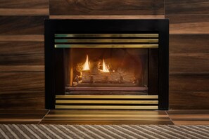 Una chimenea moderna con frente de vidrio, integrada en una pared de madera.
