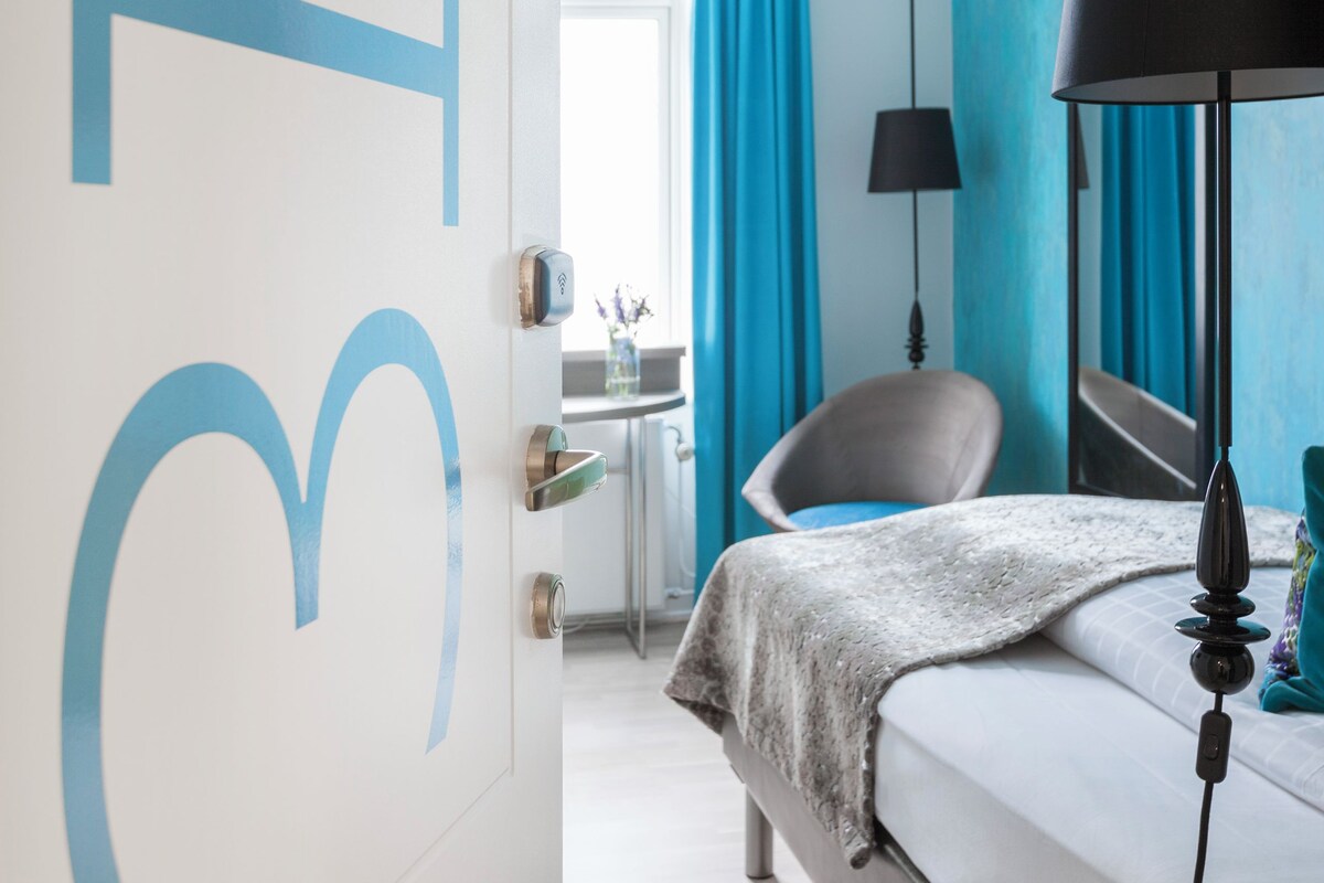 A modern hotel room with a bed, a desk, and a chair.