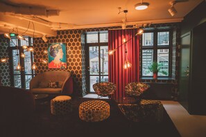 A modern interior with a sofa, ottomans, and a painting on the wall. - Andersen Boutique Hotel (Copenhagen)