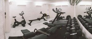 Un gimnasio con equipo de ejercicio variado, incluyendo cintas de correr, bicicletas estáticas y pesas libres.