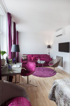 A modern living room with a sofa, chairs, a TV, and a dining area. - Andersen Boutique Hotel (Copenhagen)