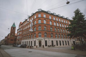 A multi-story hotel with a classic architectural style, featuring a prominent corner tower and a series of arched windows. - Andersen Boutique Hotel (Copenhagen)