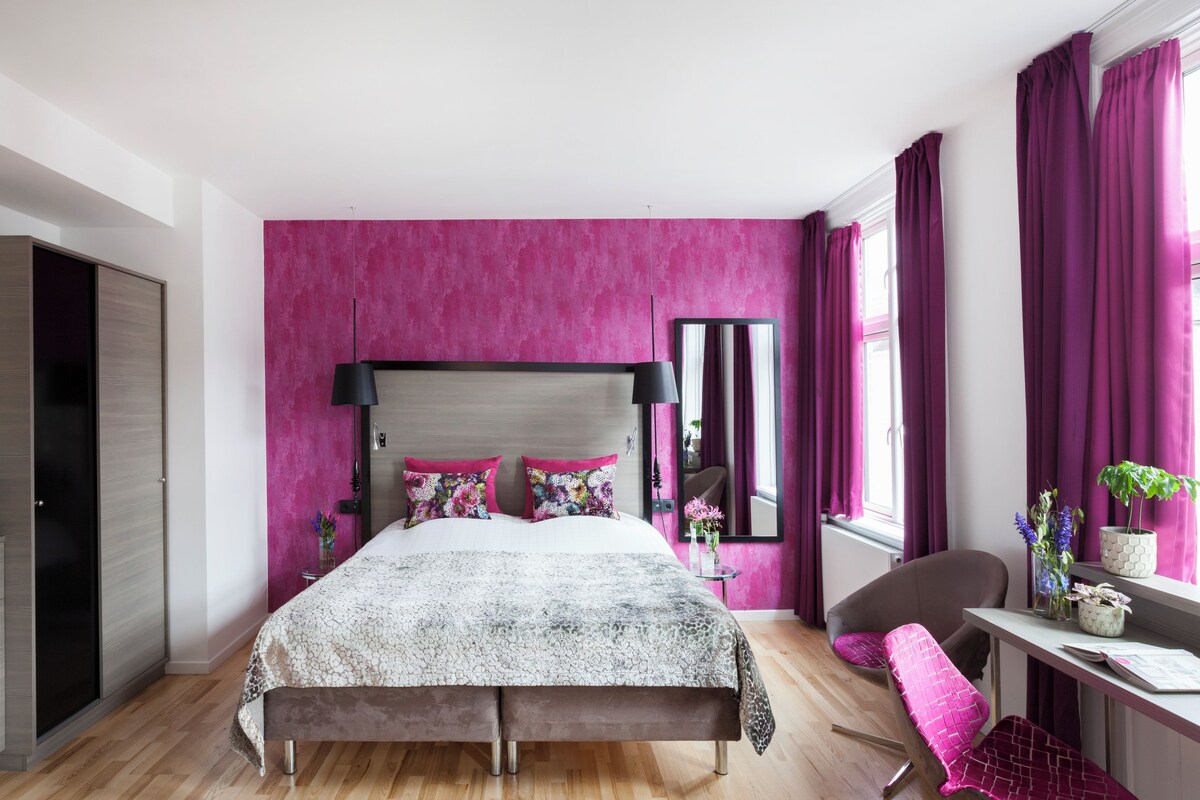 A modern bedroom with a large bed, a desk, and a chair.