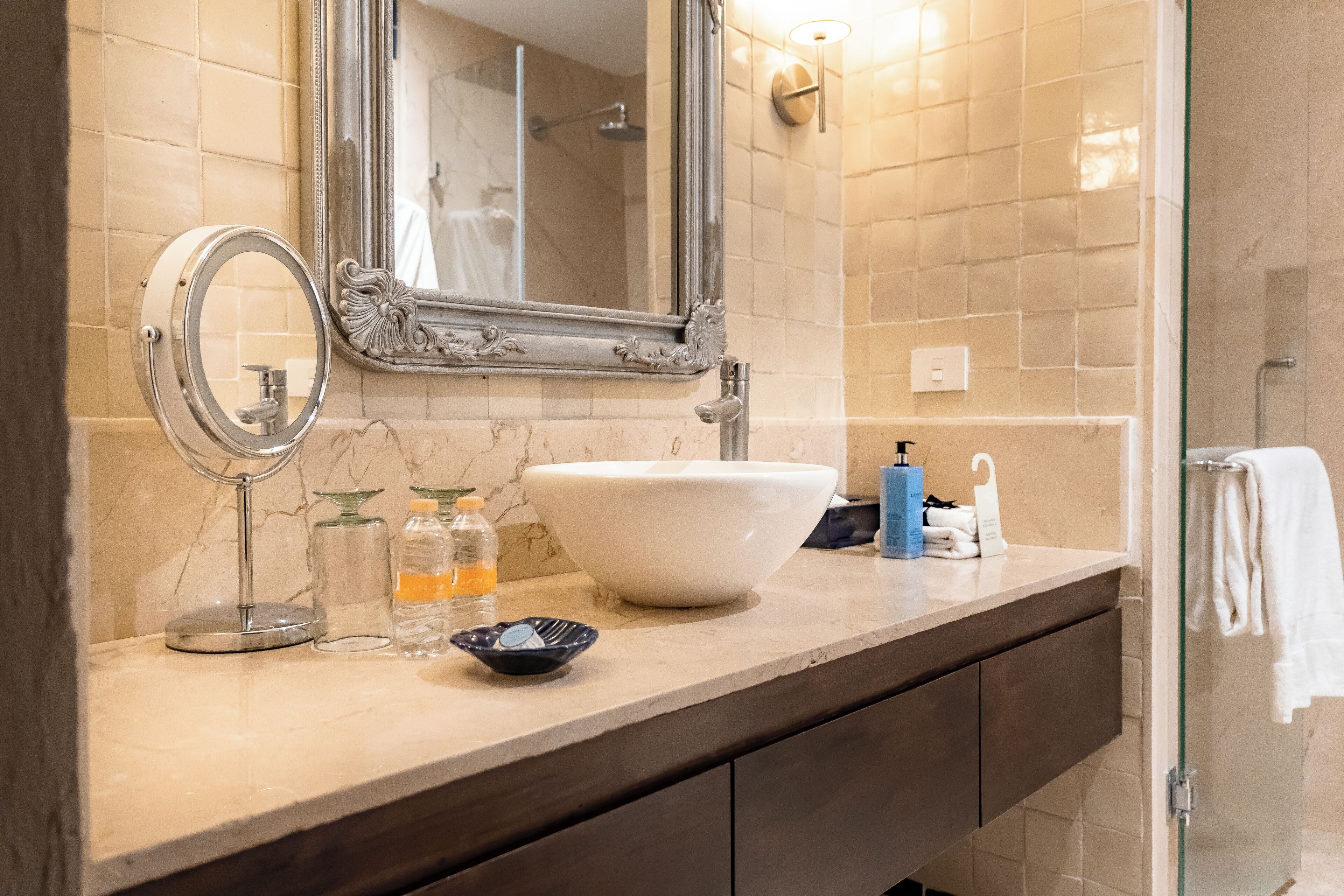 A bathroom with a large mirror, a sink, and a glass shower enclosure.