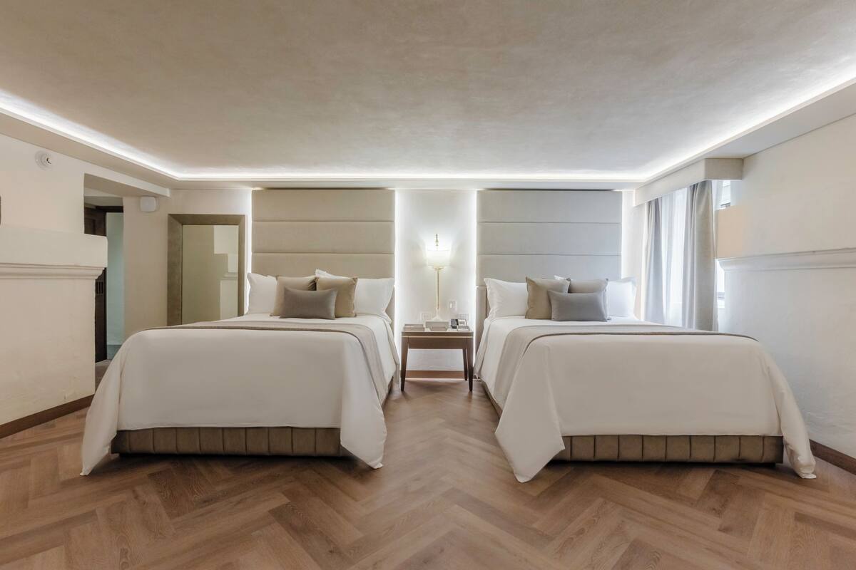 Une chambre d’hôtel avec deux lits, une table de chevet et une lampe.