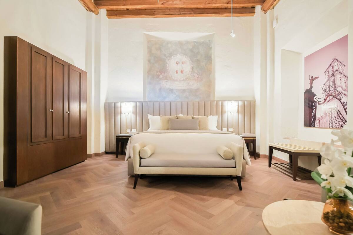 Une chambre à coucher avec un grand lit, une armoire en bois et des œuvres d’art accrochées aux murs.