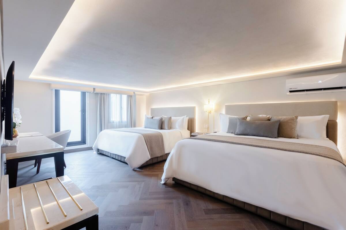 Une chambre d’hôtel avec deux lits, un bureau et une télévision.