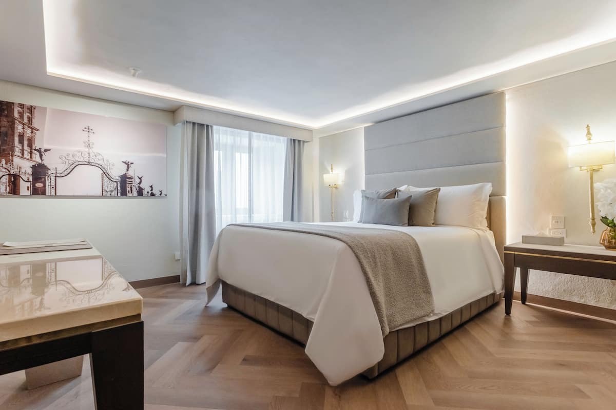 Une chambre d’hôtel moderne avec un grand lit, une table de chevet avec une lampe et une œuvre d’art accrochée au mur.