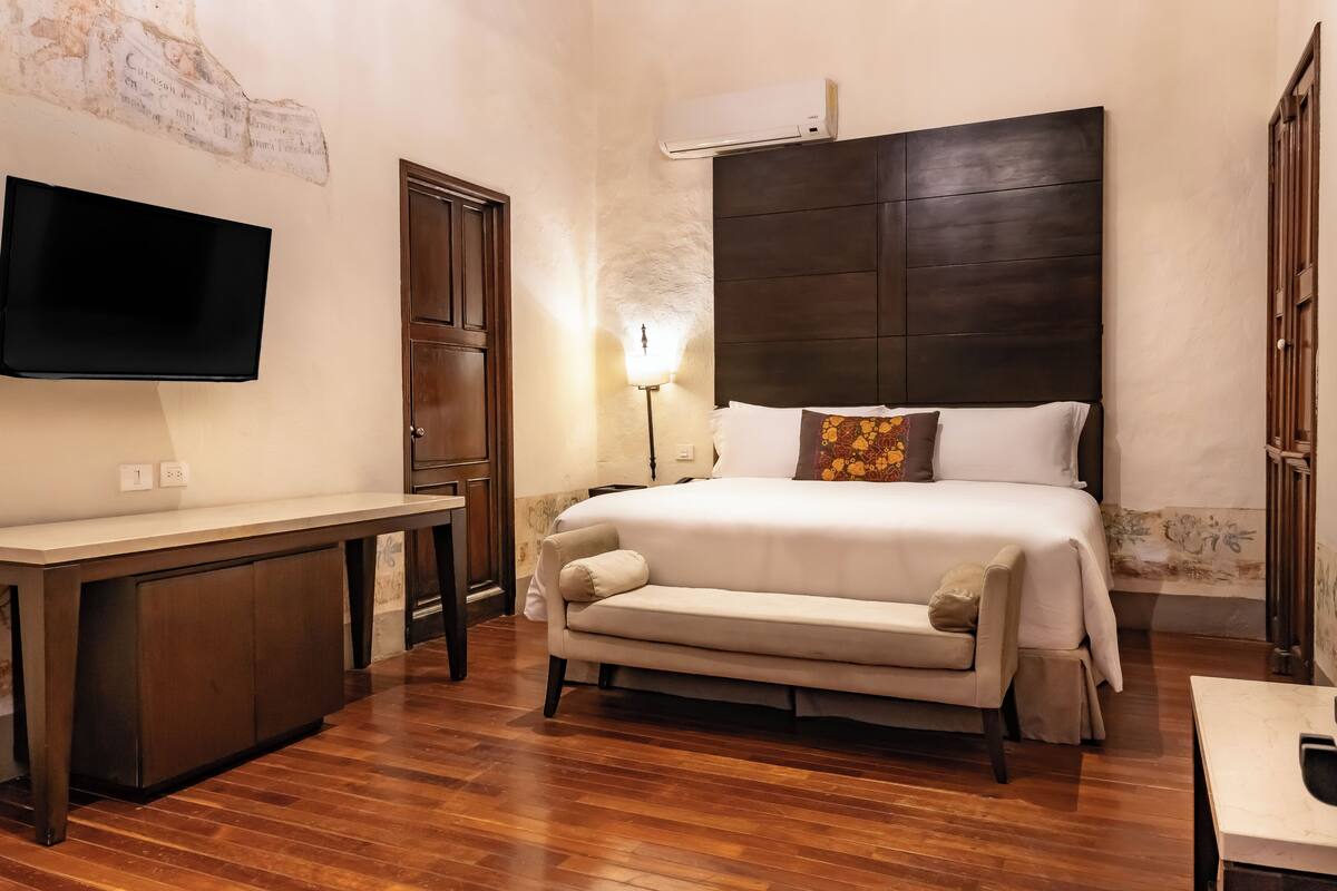 Une chambre d’hôtel avec un lit, un bureau, une télévision et une lampe.