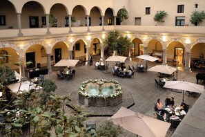 An indoor courtyard with multiple dining areas, a central fountain, and arches. - Quinta Real Puebla (Puebla)
