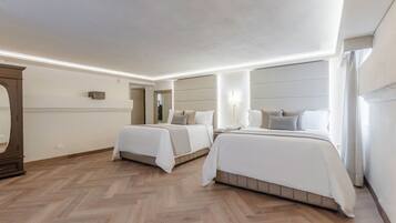 Habitación de hotel con dos camas, un espejo grande y suelo de madera con diseño de espiga.