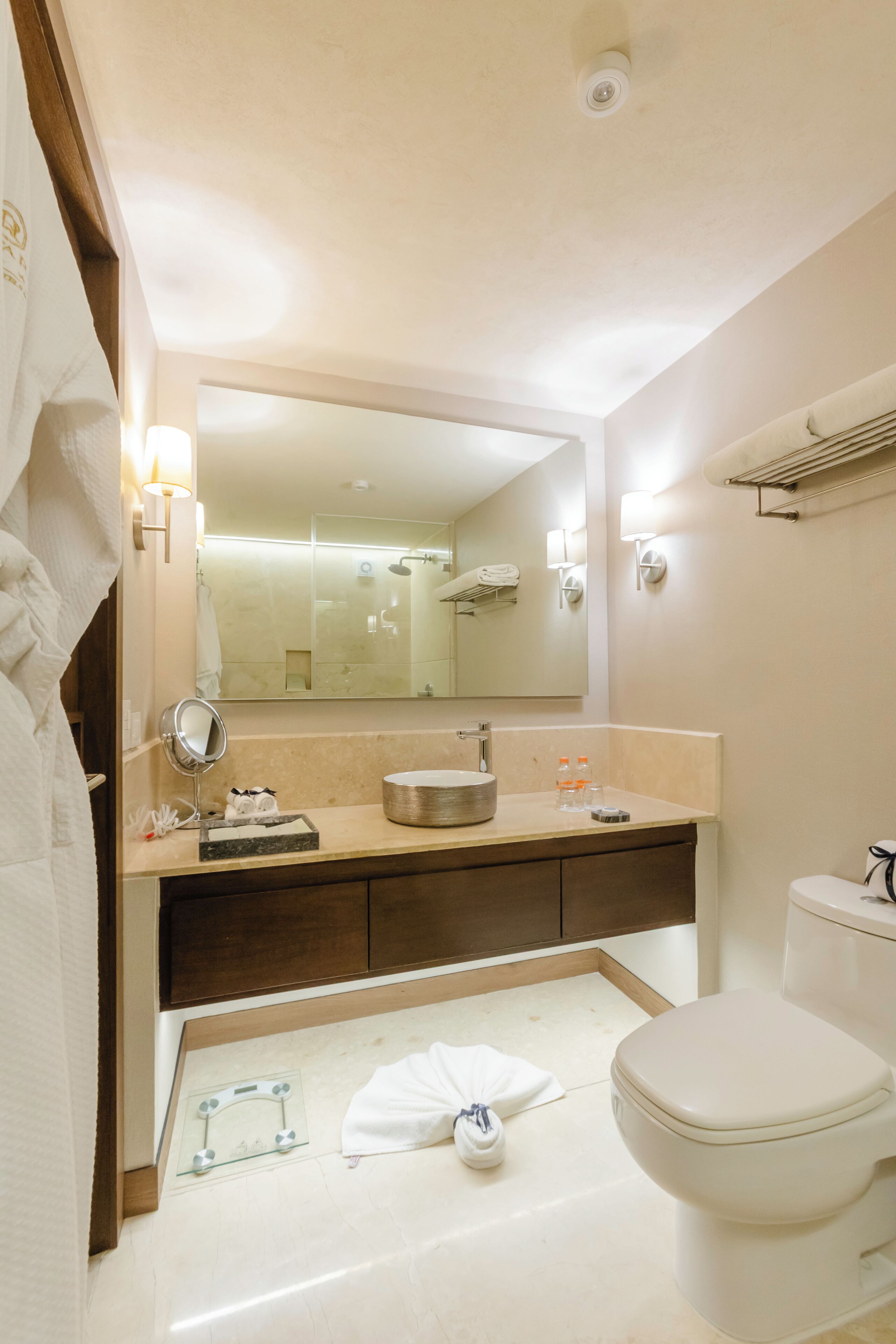 A modern bathroom with a large mirror, a sink, a toilet, and a towel rack.