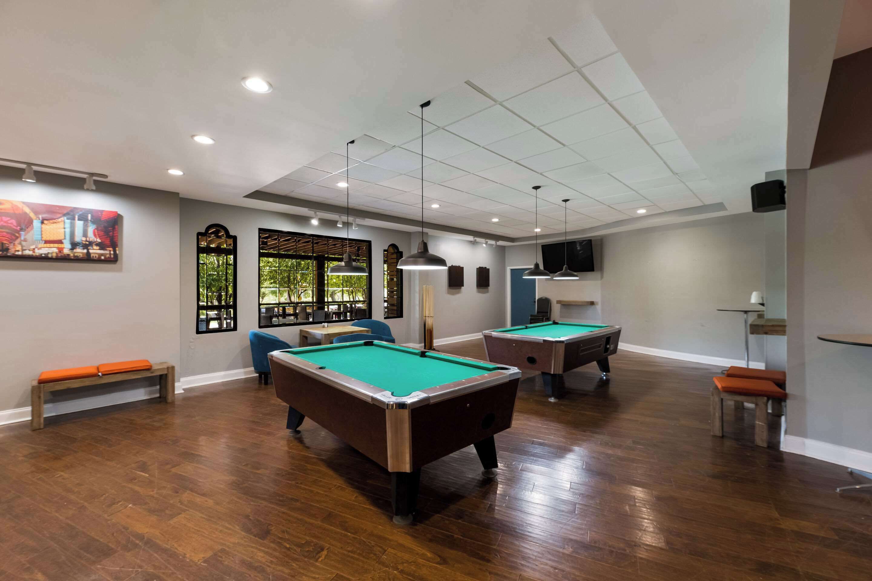 Une salle de billard équipée de deux tables de billard, de bancs et d’un plafond doté d’un éclairage encastré.