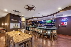 A bar area with a counter, bar stools, and a large screen displaying sports. - Clarion Hotel San Angelo near Convention Center (San Angelo)