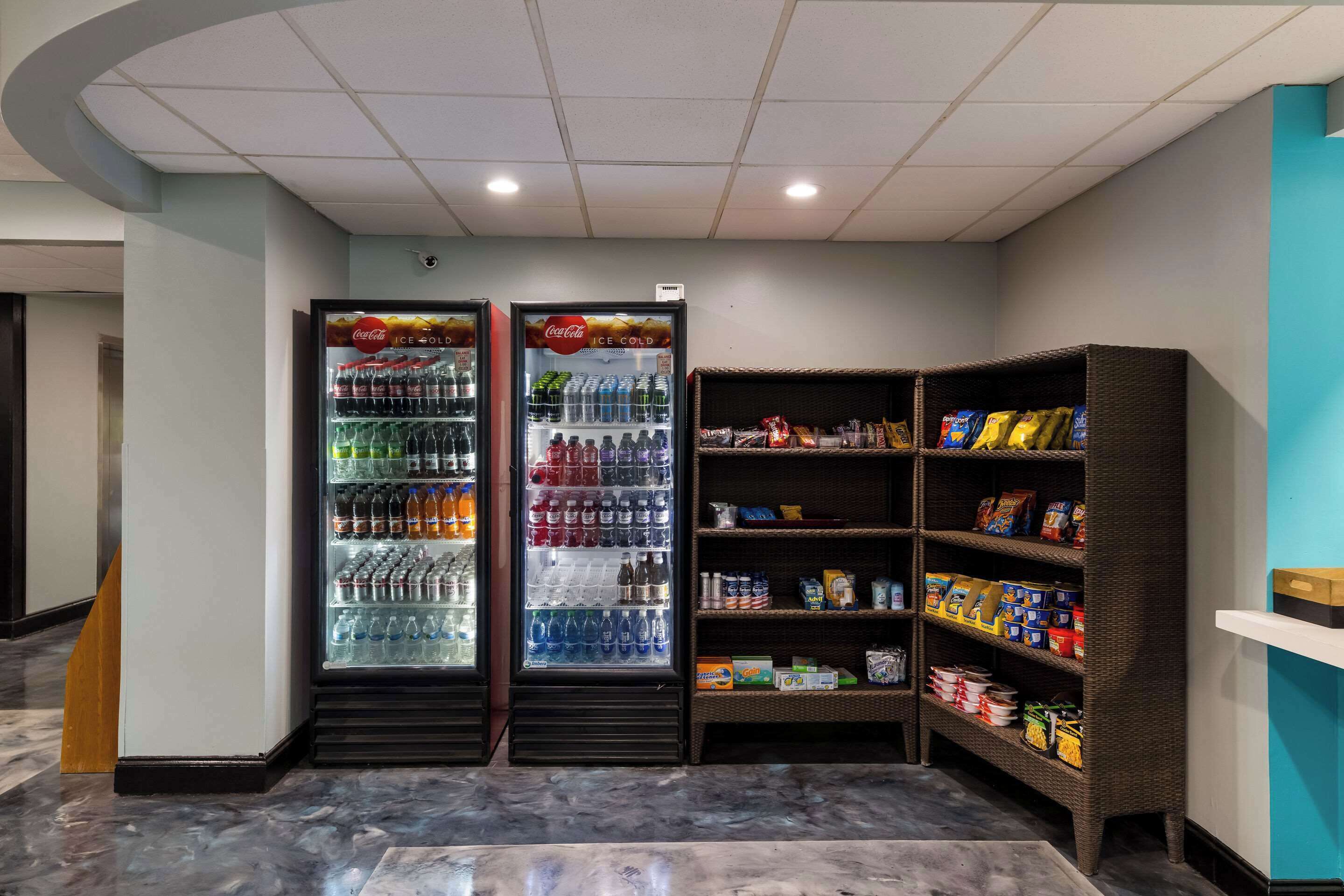 Un área de venta con dos refrigeradores de Coca-Cola y un estante lleno de refrigerios.