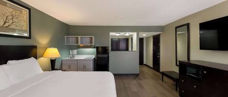 Une chambre d’hôtel équipée d’un lit, d’un bureau, d’une kitchenette et d’un téléviseur.