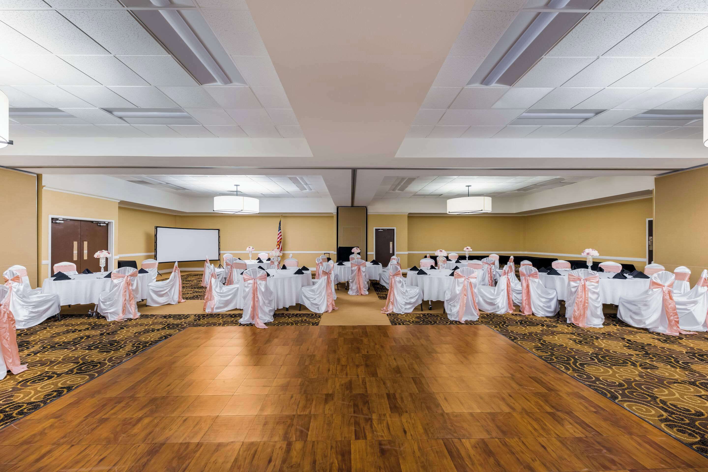 A conference room with rows of tables, a projector screen, and an American flag.