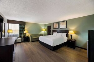 Una habitación de hotel con cama, escritorio, silla y refrigerador.