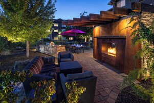 Un patio exterior con una chimenea, zona de estar y mesas de comedor.