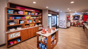 A store with shelves of snacks, a display of clothing, and a refrigerator. - Hampton Inn Pullman (Pullman)