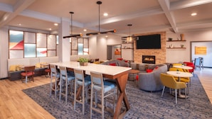 A modern lounge area with a wooden table, bar stools, and a fireplace. - Hampton Inn Pullman (Pullman)