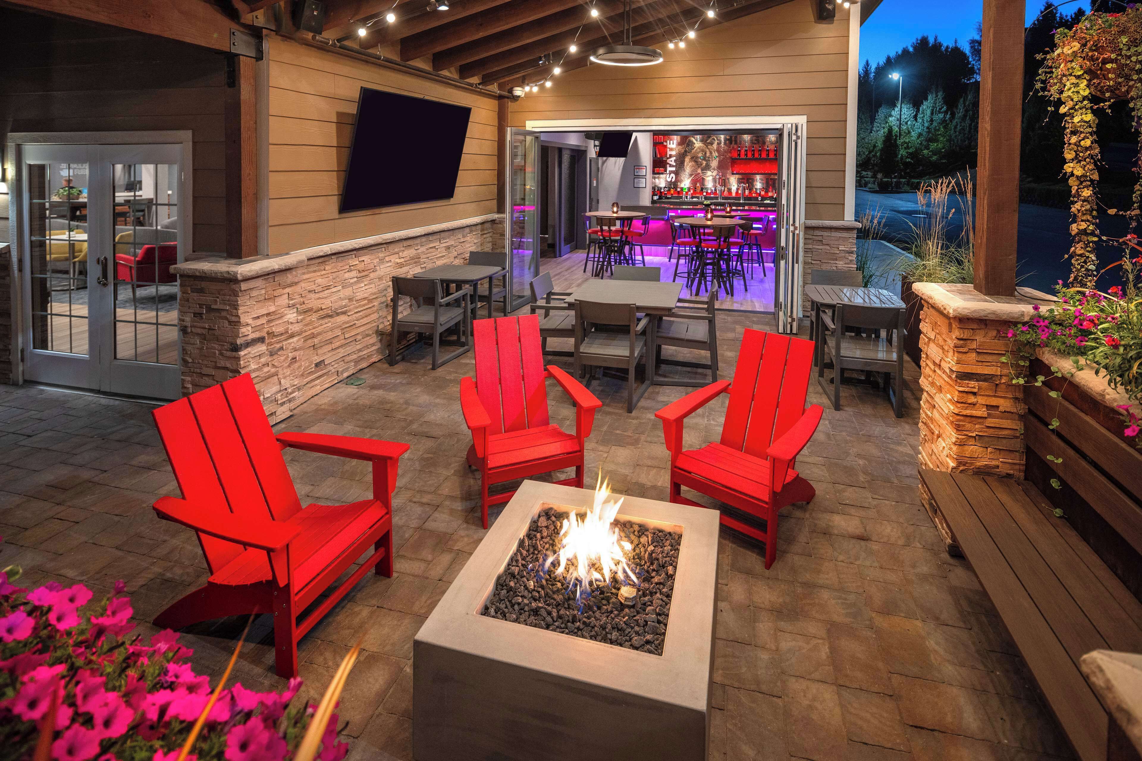 Une terrasse extérieure avec des chaises rouges, un foyer et un espace bar avec des sièges.
