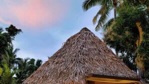 A thatched-roof hut with a bed and a small porch, surrounded by tropical vegetation and a pond with lily pads. - The Westin Fiji Golf Resort & Spa (Nadi)