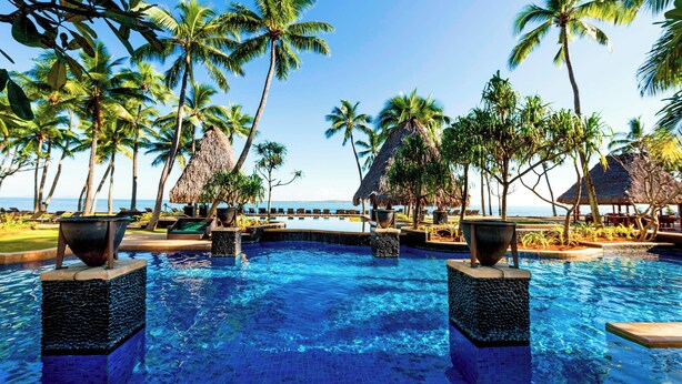 A pool area with palm trees, a thatched-roof structure, and a view of the ocean. - The Westin Fiji Golf Resort & Spa (Nadi)