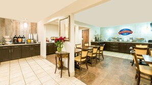 A spacious kitchen with a breakfast bar, modern appliances, and a dining area with wooden chairs and a vase of flowers. - Baymont by Wyndham Louisville East (Louisville)