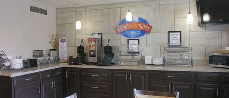 A breakfast corner with a sign, toaster, coffee maker, and a microwave.
