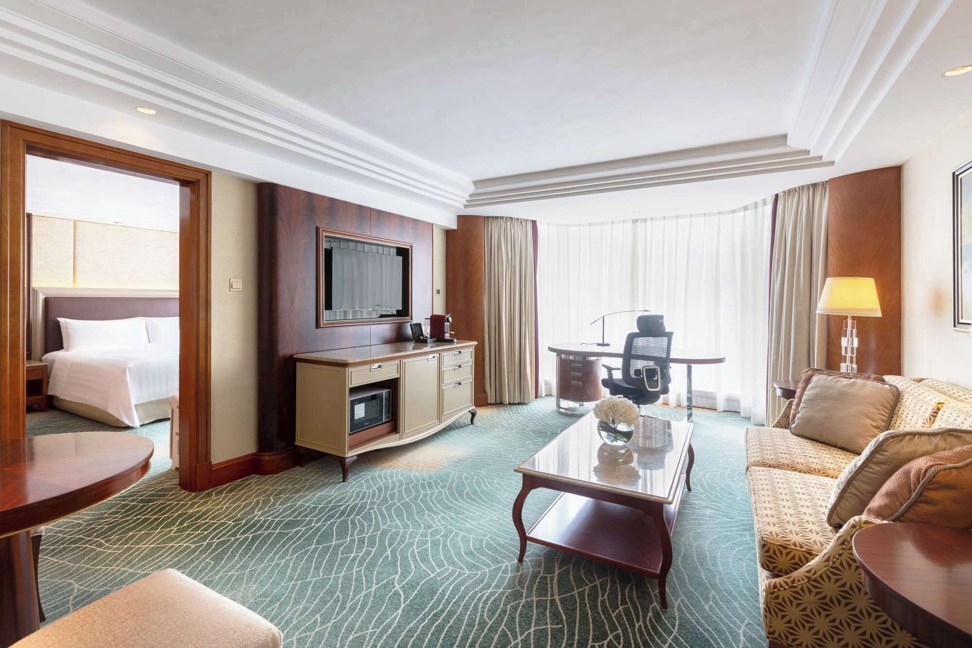 Una habitación de hotel con una cama, un escritorio con computadora, televisor, mesa de centro y sofá.