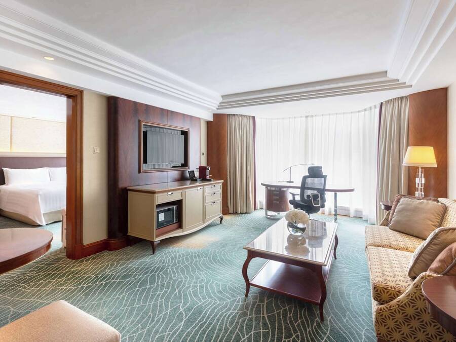 Una habitación de hotel con una cama, un escritorio con computadora, televisor, mesa de centro y sofá.