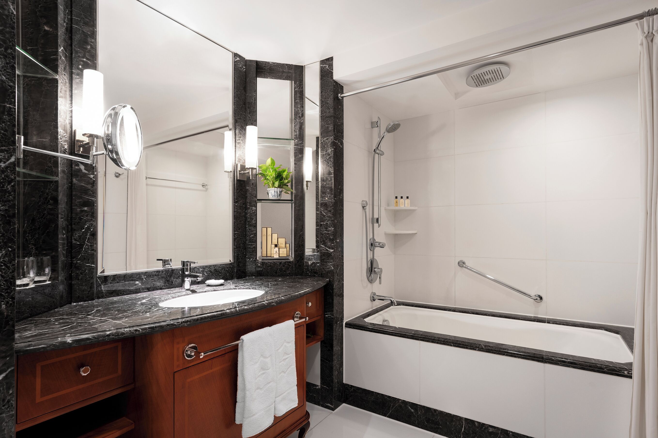 A bathroom with a marble countertop, a sink, a mirror, a shower, and a bathtub.