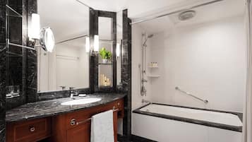 A bathroom with a marble countertop, a sink, a mirror, a shower, and a bathtub.