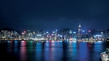 A nighttime cityscape with illuminated buildings reflecting on the water.