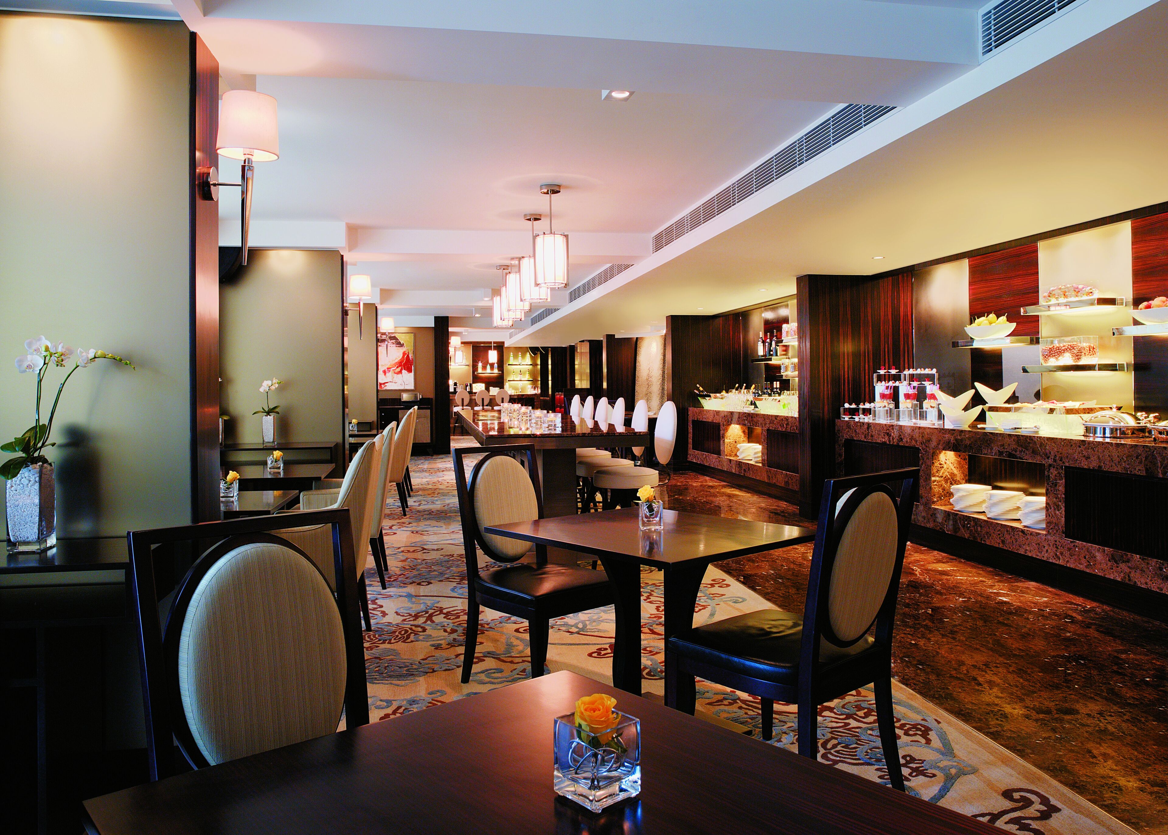 Eine Hotelhalle mit Rezeption, einer Sitzecke und einem Frühstücksbuffet.