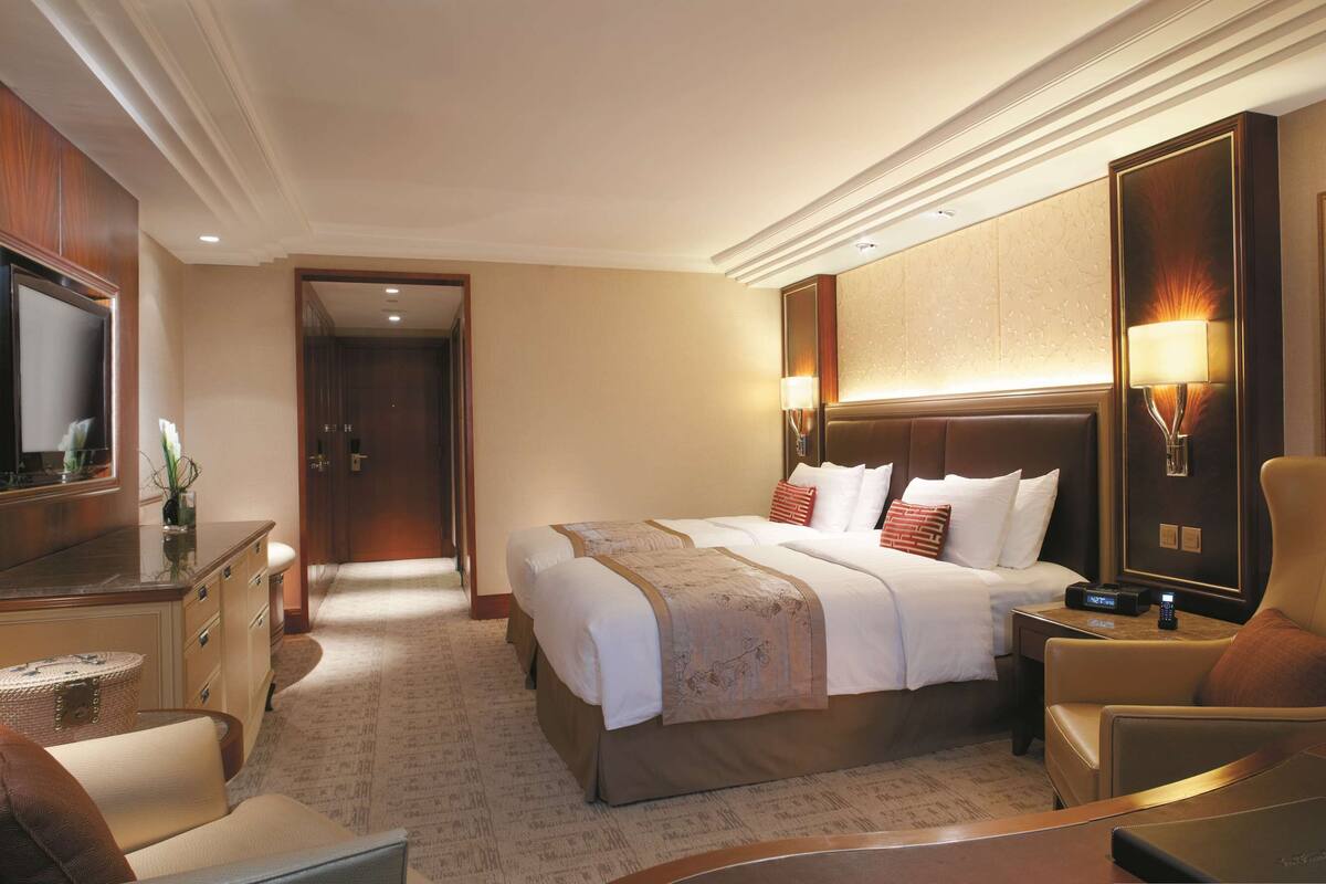 A hotel room with a large bed, a desk, a chair, a TV, and a framed picture on the wall.