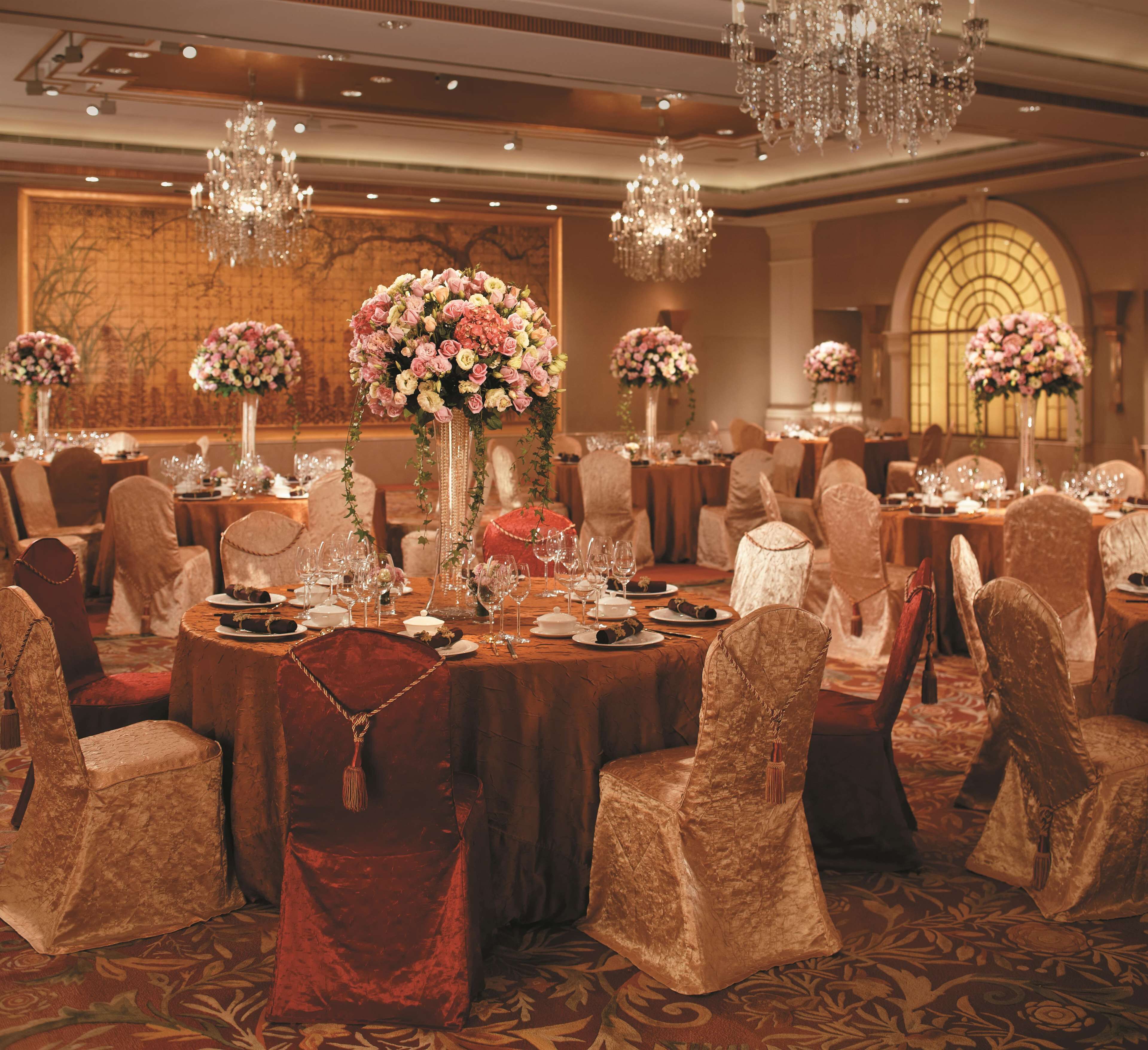 Une salle de banquet avec des tables rondes, des chaises et des lustres.