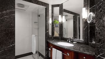 Un baño moderno con tocador de mármol, un espejo grande y una cabina de ducha de vidrio.