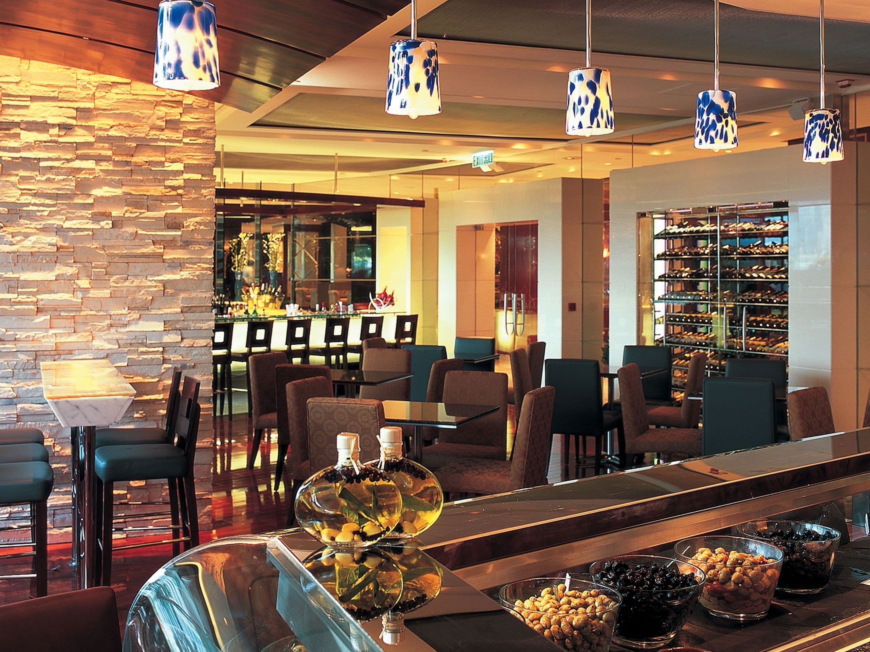 A modern bar area with seating, a wine rack, and decorative lighting.