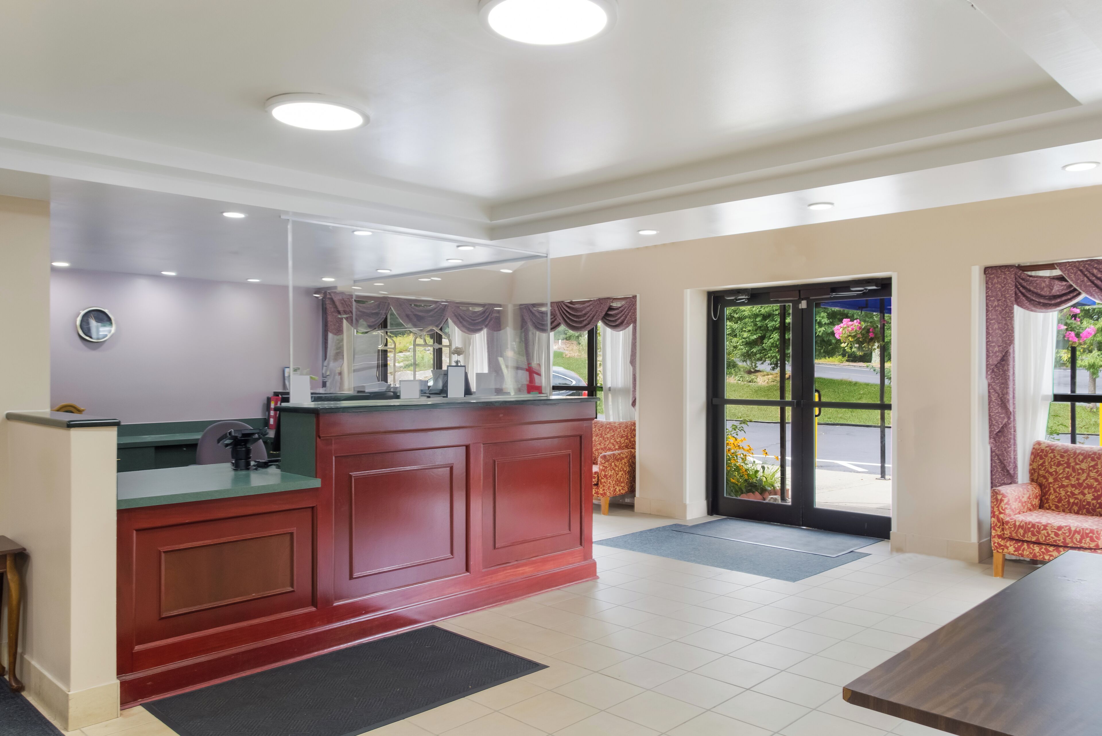A reception area with a red counter, a waiting area with chairs, and a glass door leading outside.