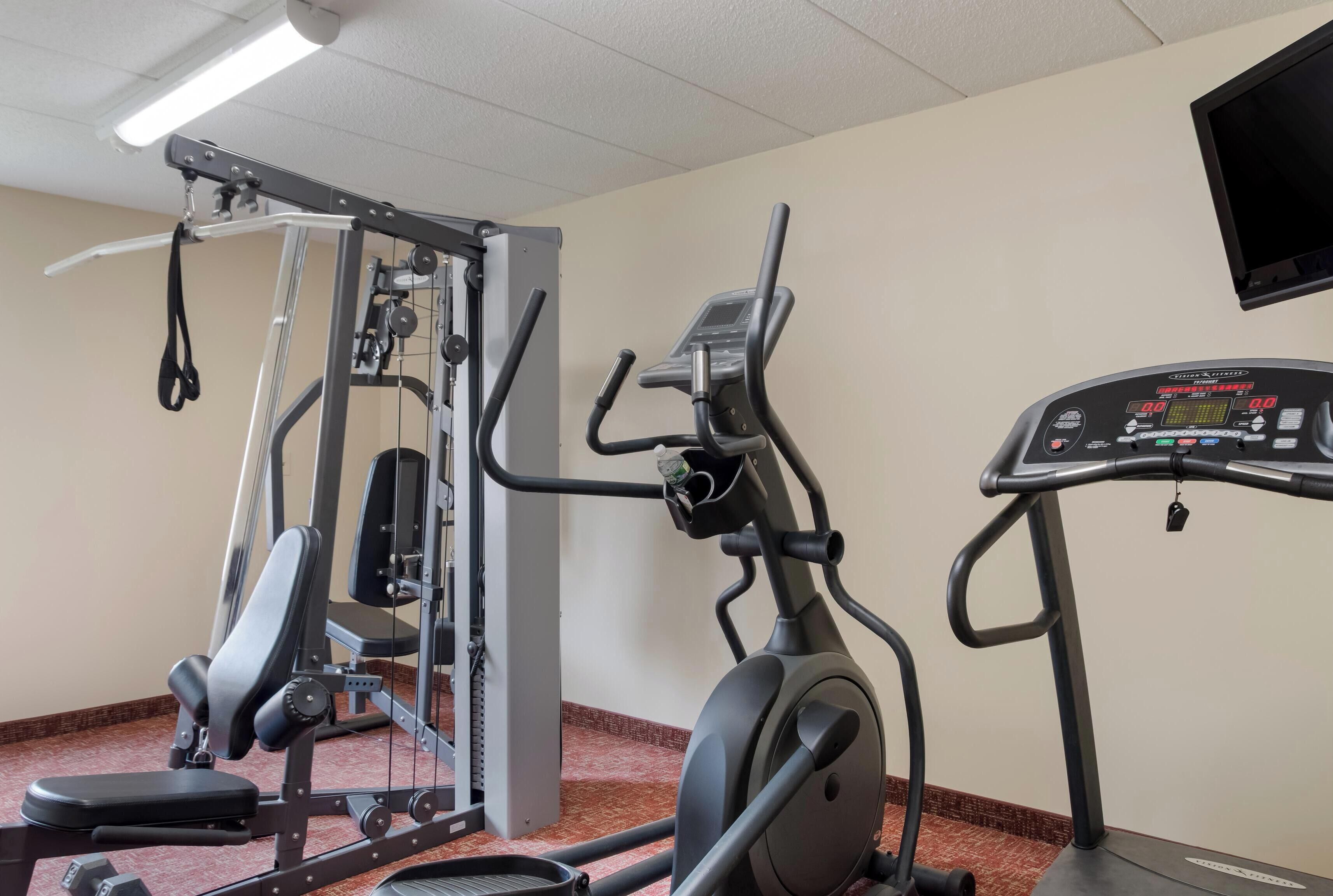 Ein Fitnessstudio mit Kraftmaschine, Crosstrainer und Laufband.