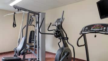 Un gimnasio con una máquina de pesas, una elíptica y una cinta de correr.