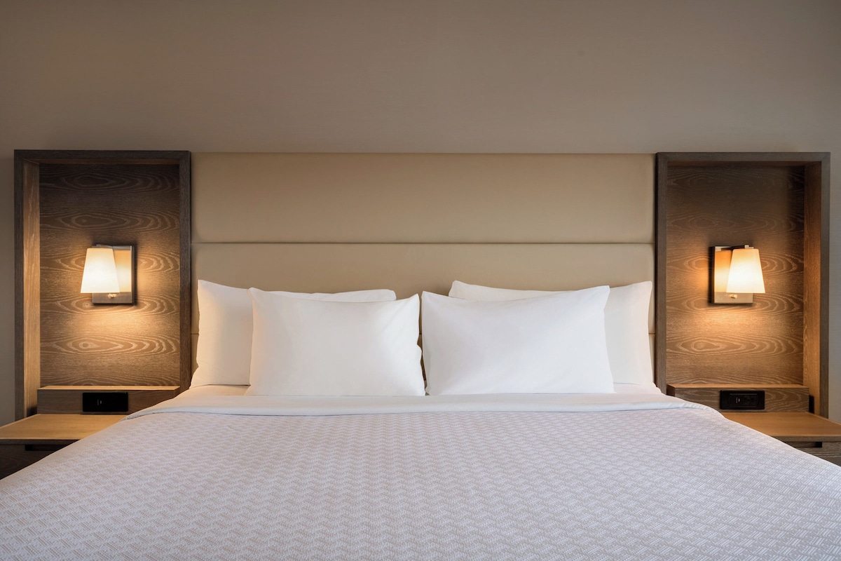 Een hotelkamer met een groot bed, twee nachtkastjes en wandlampen.