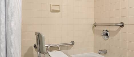 A bathroom with a bathtub, grab bars, and a towel rack.