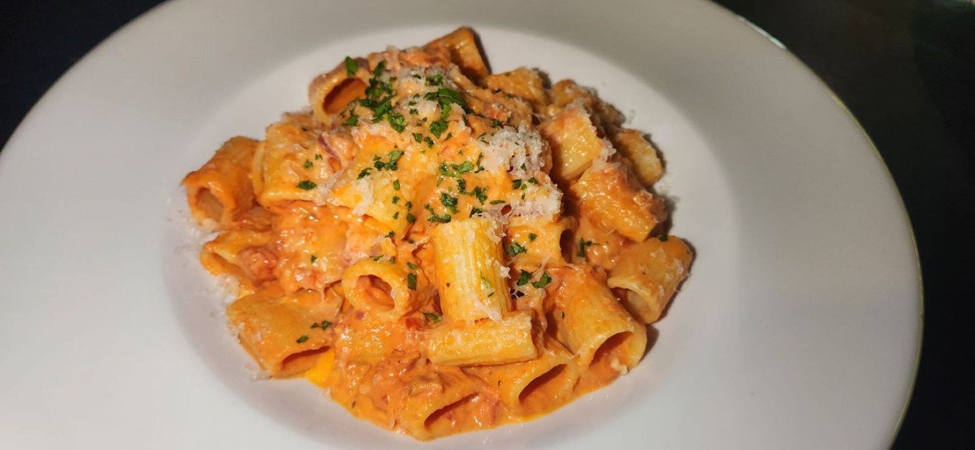 Un plato de pasta con salsa cremosa, adornado con hierbas y queso rallado.
