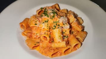 Un plato de pasta con salsa cremosa, adornado con hierbas y queso rallado.