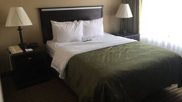 A hotel room with a bed, two bedside tables, a lamp on each table, a telephone, and a window with curtains.