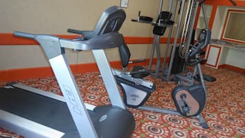 Une salle de sport équipée de tapis de course, d’appareils de musculation et d’un tapis à motifs.